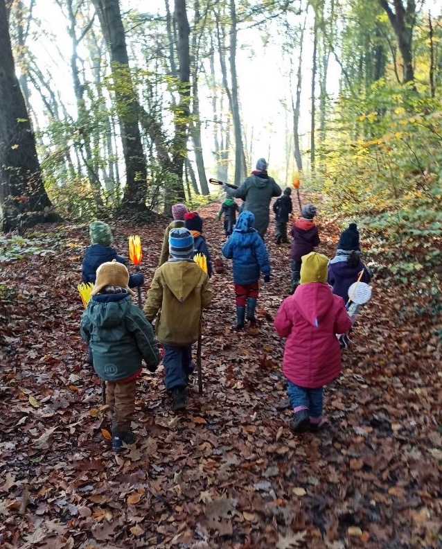 Kinder laufen mit Laternen durch den Wald